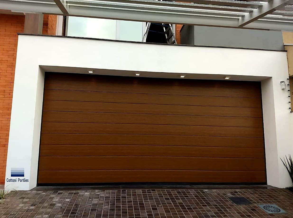 Portão seccional amadeirado escuro Cattani sob pergolado